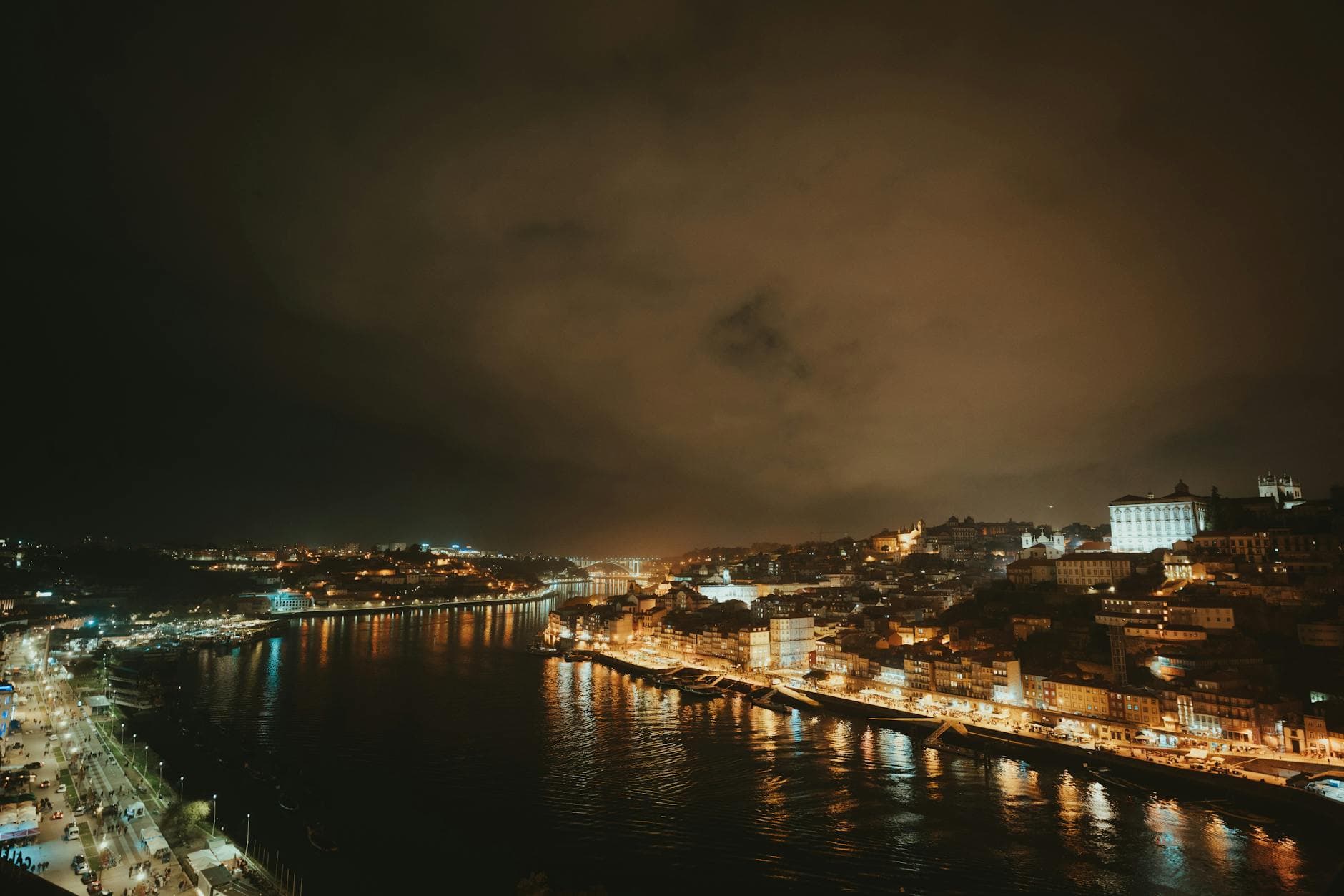 Gorgeous nighttime panorama of Porto cityscape with illuminated riverbanks and buildings.