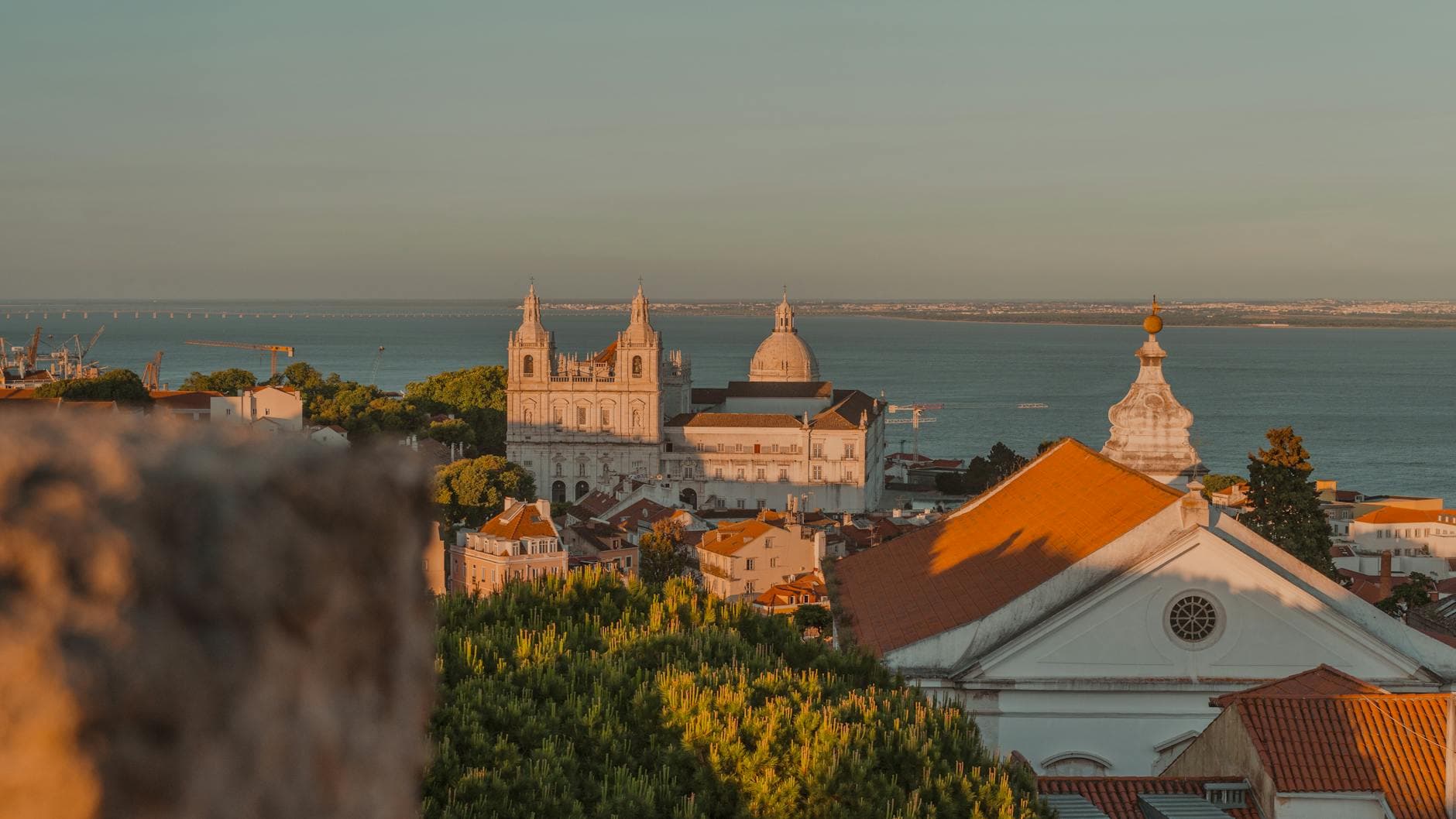 A stunning view of Lisbon showcasing historic architecture against the backdrop of the sea at sunset.