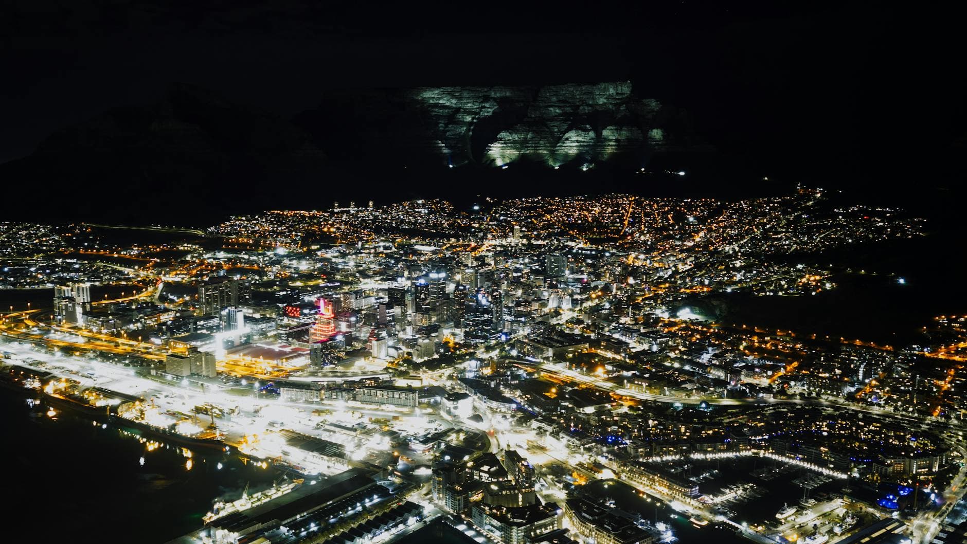 Stunning night aerial view of Cape Town city lights with majestic Table Mountain in the background.
