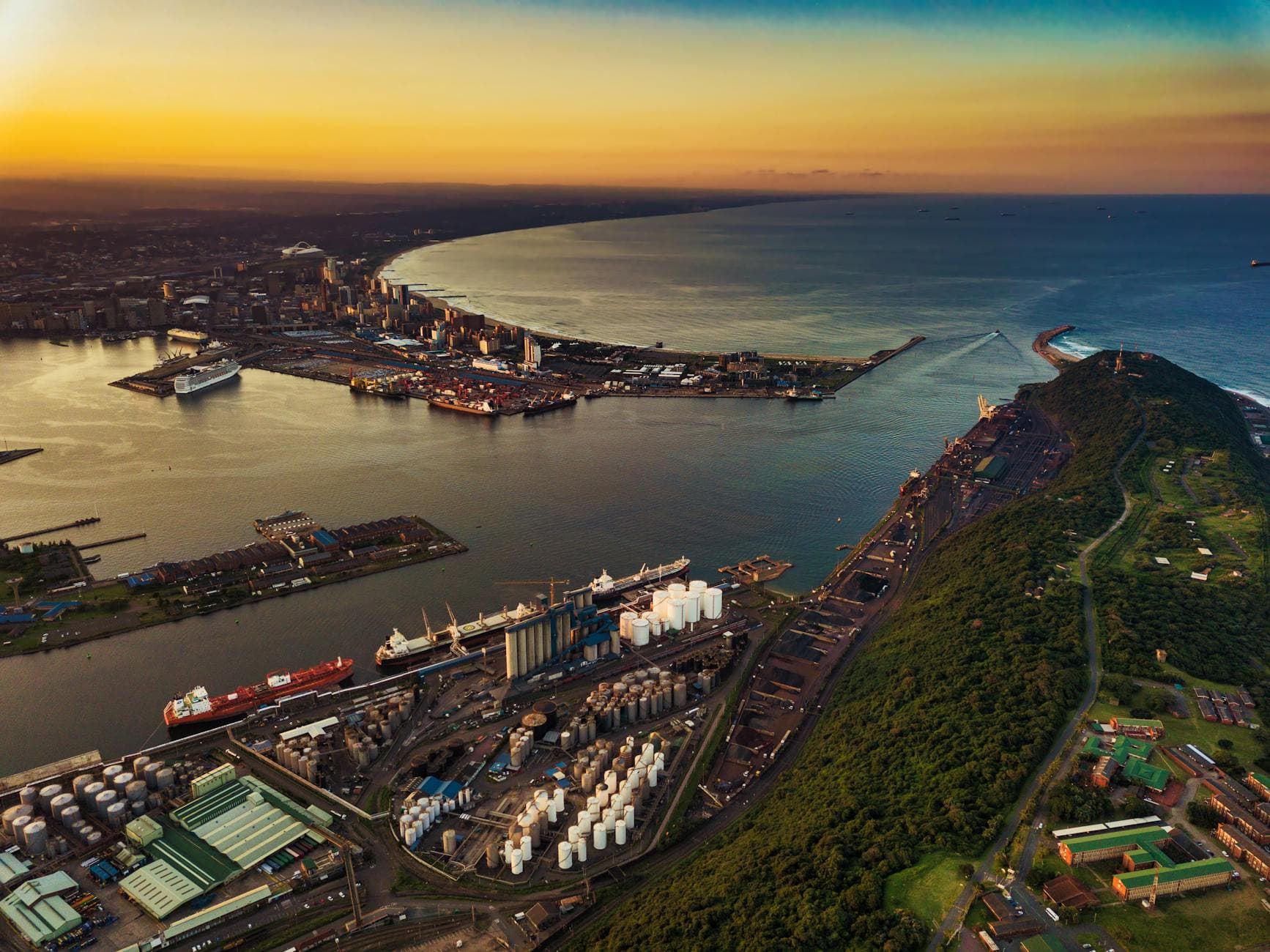A vibrant aerial view of Durban harbor during sunset showcasing the Indian Ocean and city skyline.
