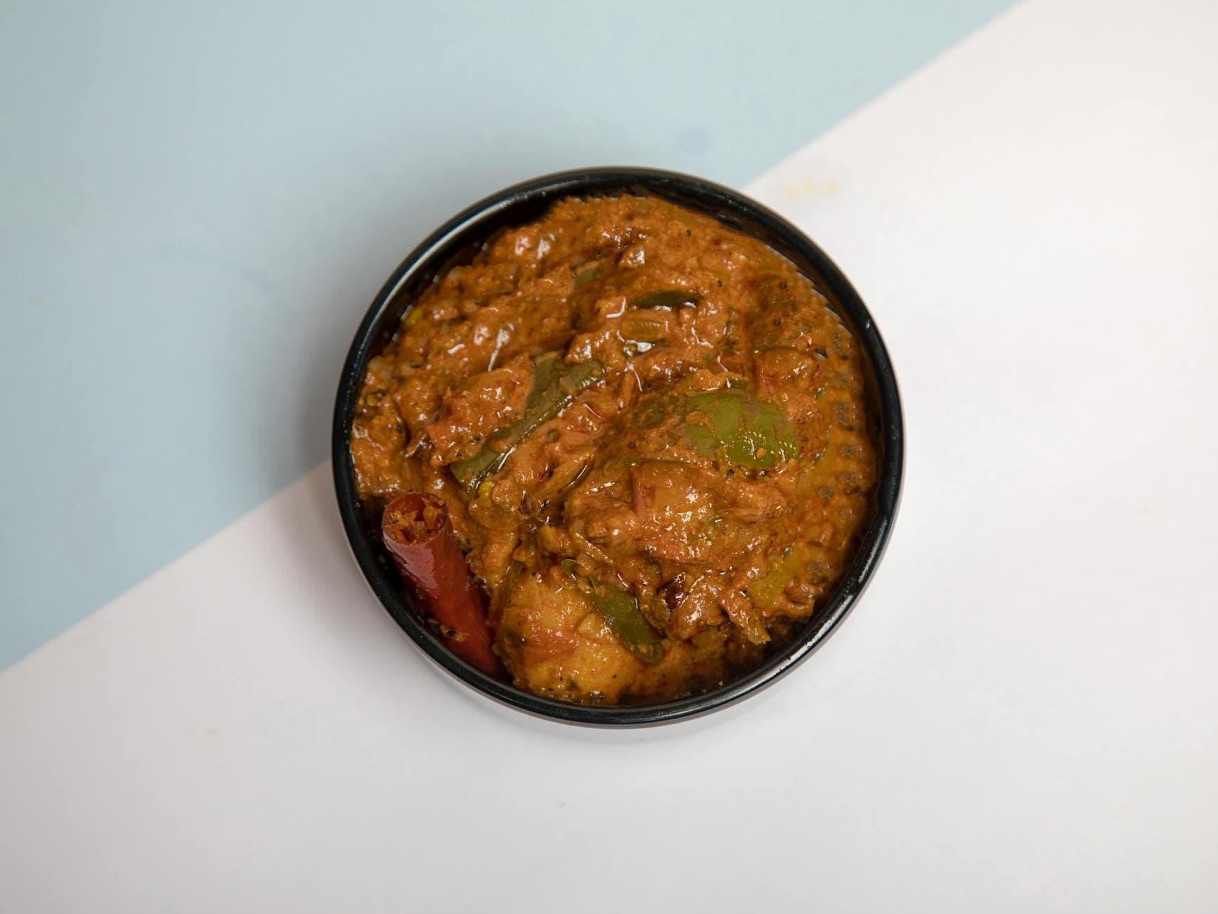 Top-down view of flavorful Indian vegetable curry in a black bowl, perfect for food presentations.
