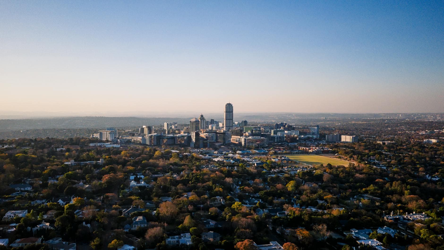 Stunning aerial view of Sandton, Gauteng, showcasing urban skyline and suburban layout under a clear sky.