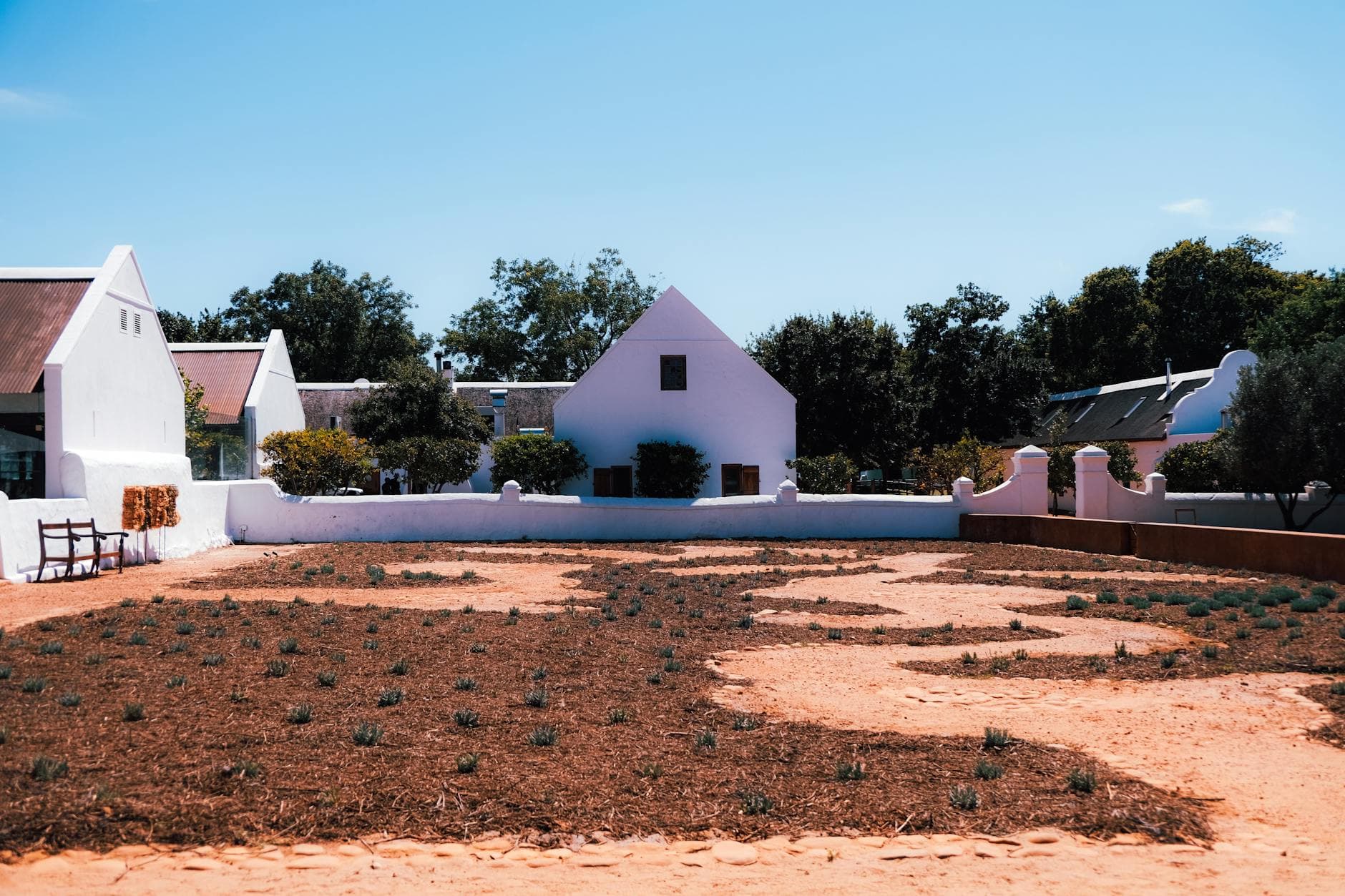 White house with a garden landscape under clear blue sky, offering a serene outdoor view.