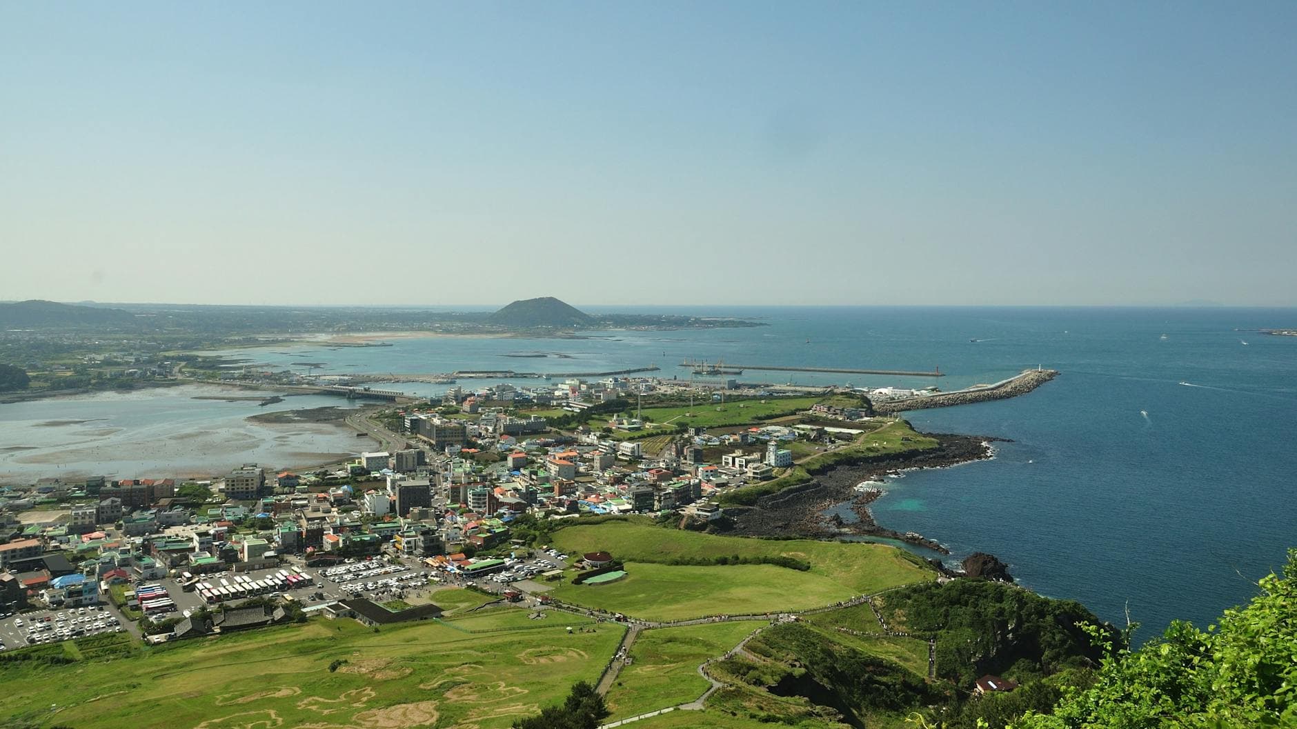 A breathtaking aerial view of Jeju Island's coastline, showcasing the vibrant city and blue ocean.