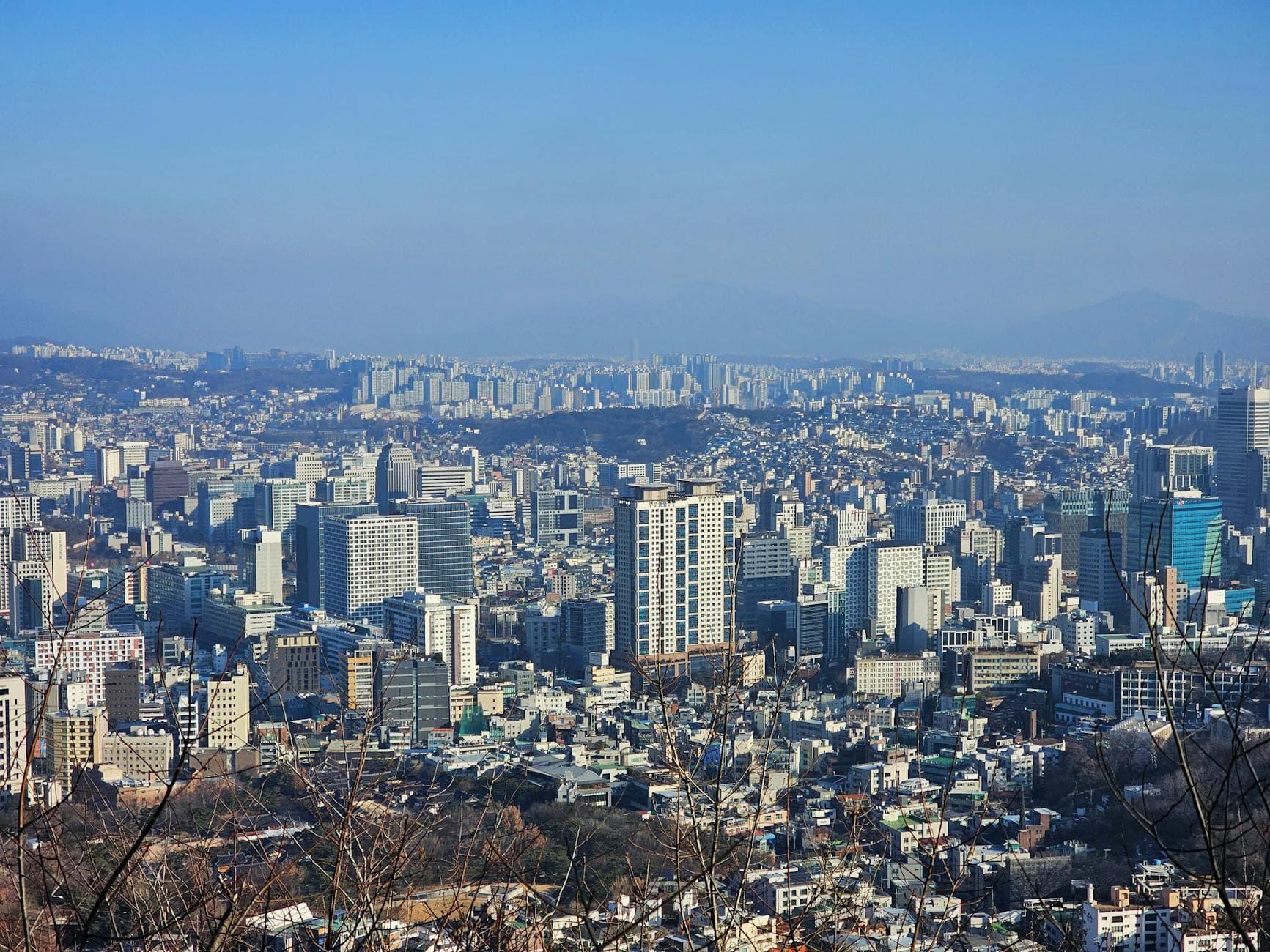 Stunning aerial view of Seoul's urban skyline, showcasing dense skyscrapers and clear blue skies.