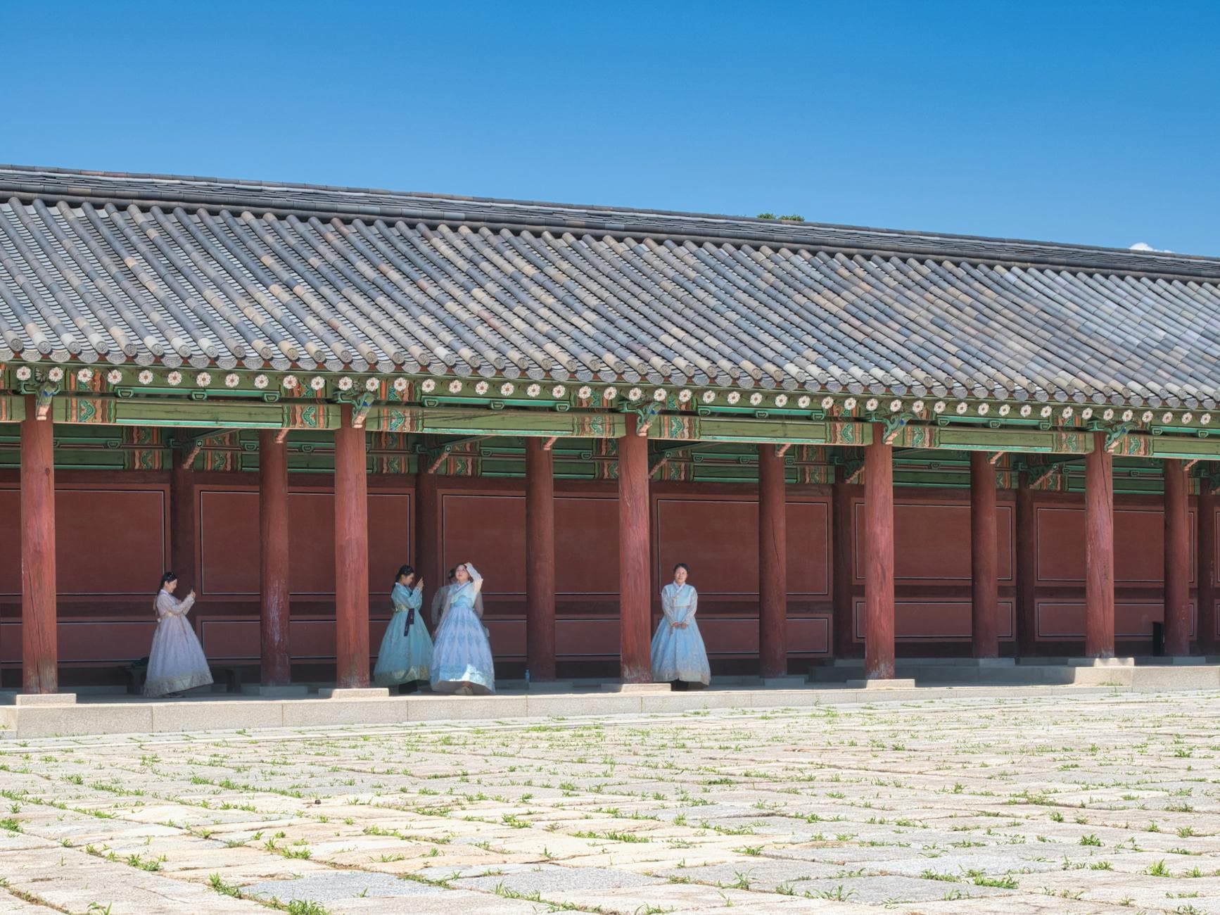 Women in traditional Korean hanbok stand by a historical palace in Seoul, showcasing cultural heritage.