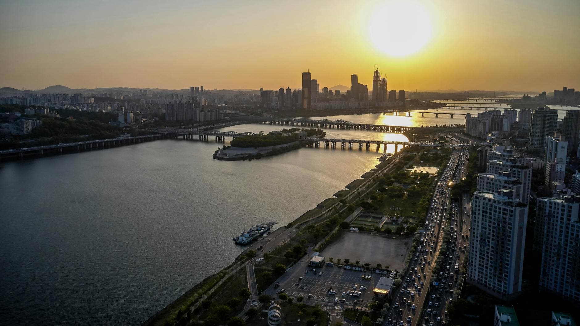 Stunning aerial view of a bustling city skyline with a river and bridge at sunset.
