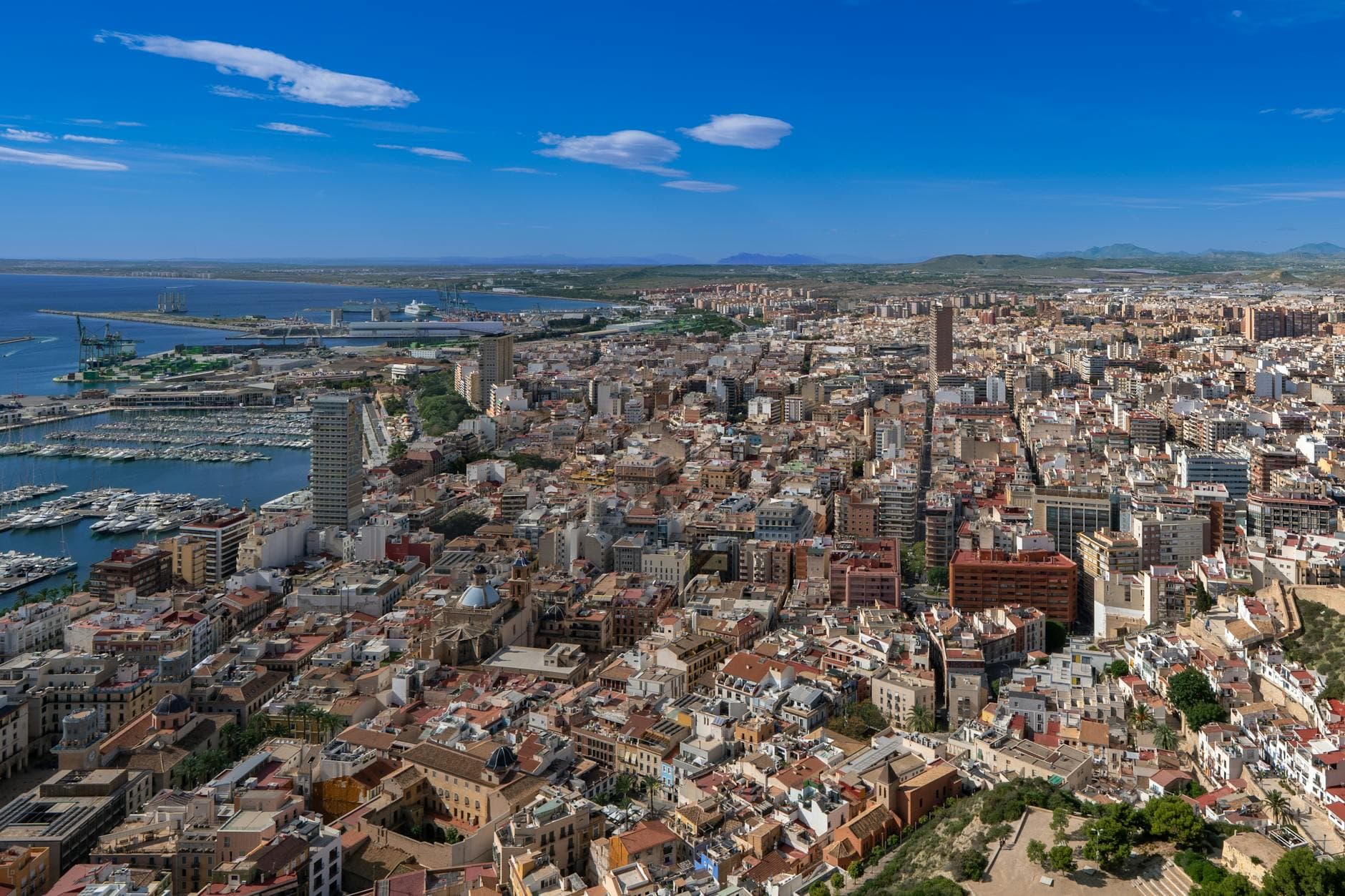 Aerial view of Alicante showcasing the bustling harbor and city skyline under a clear blue sky.