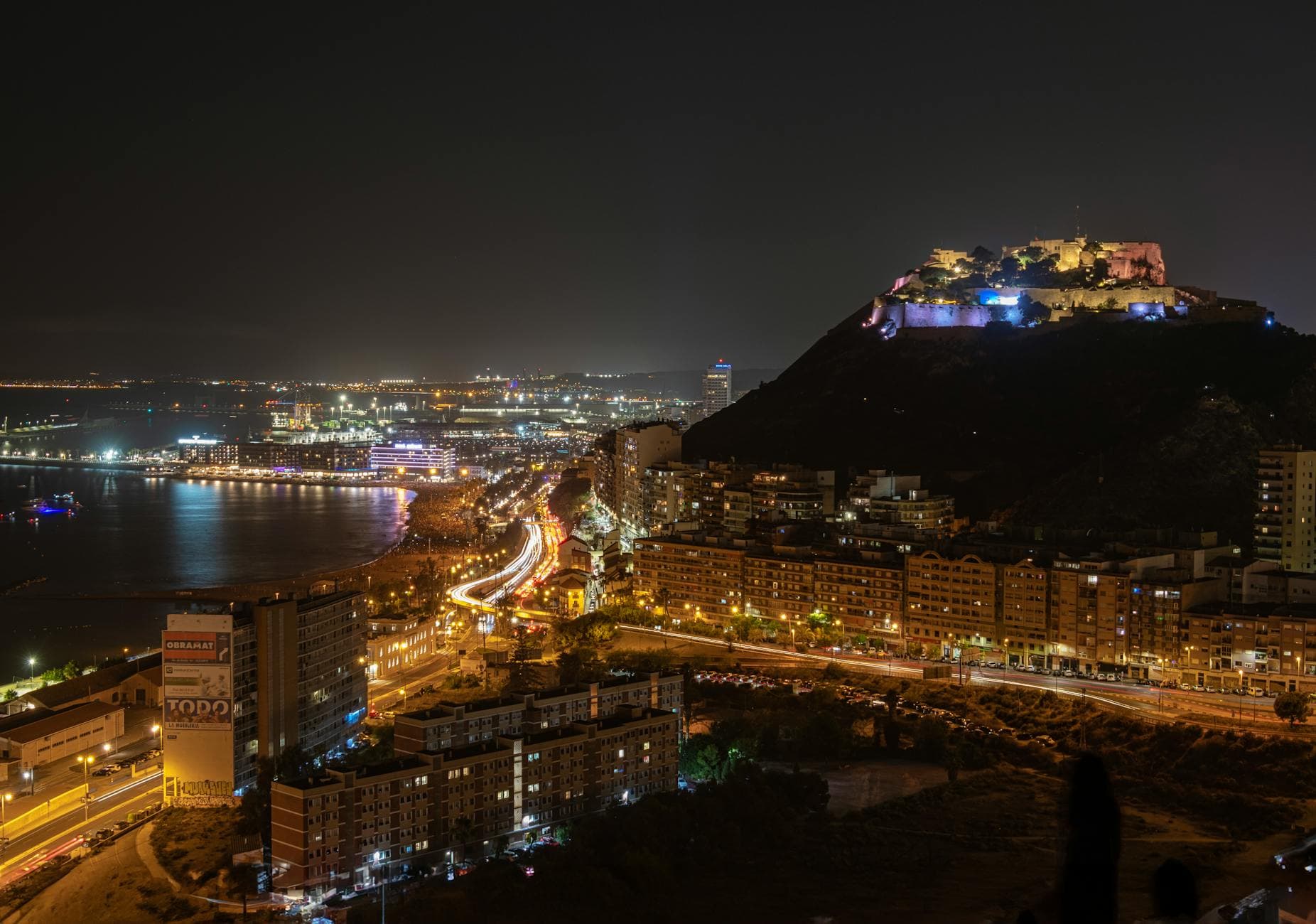 A breathtaking night view of Alicante with city lights and the Mediterranean Sea illuminating the scene.