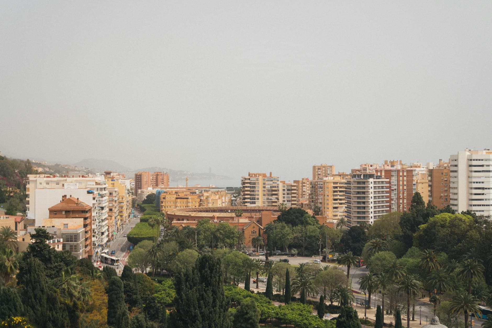 A cityscape with apartment buildings, park, and foggy skyline in Malaga, Spain.