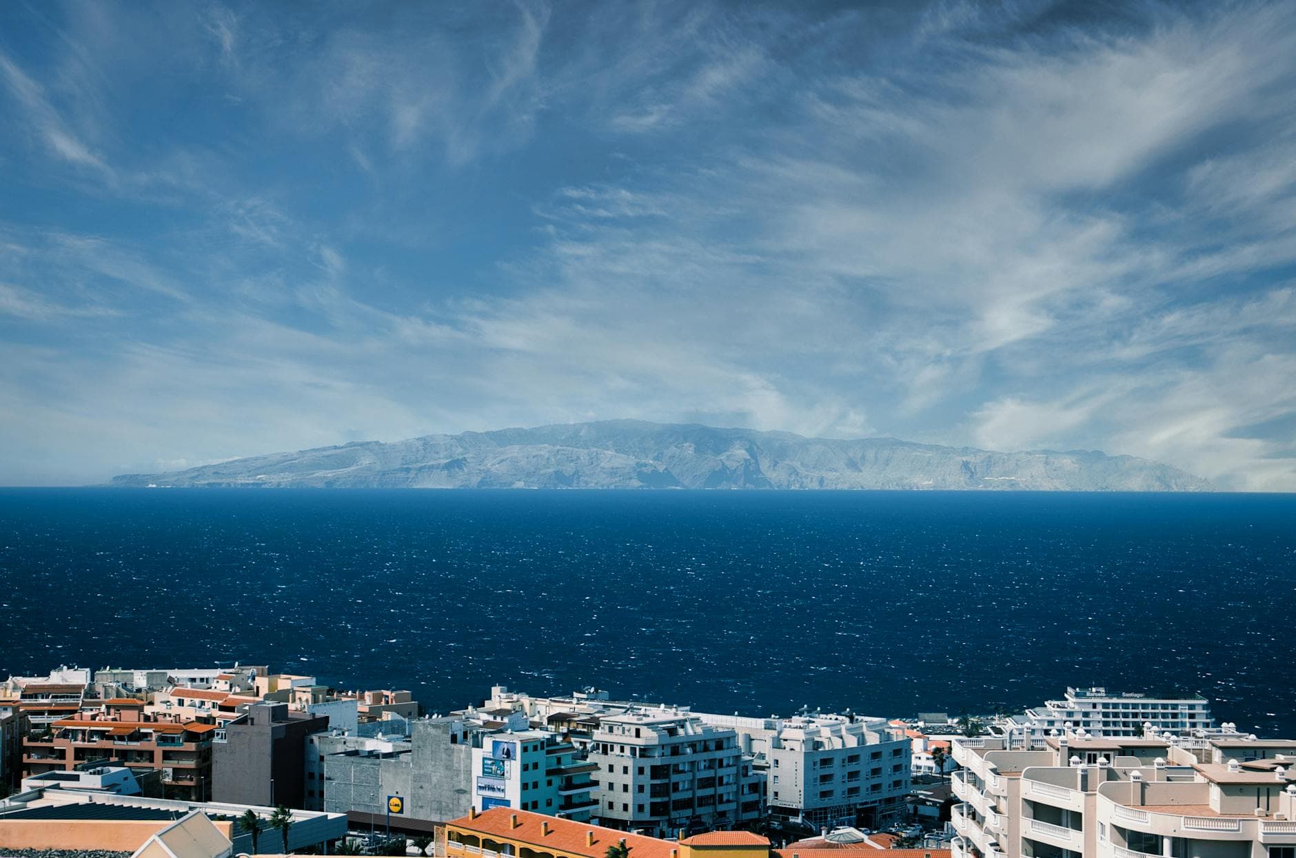 Stunning view of Tenerife cityscape with ocean and mountains under a dramatic sky.