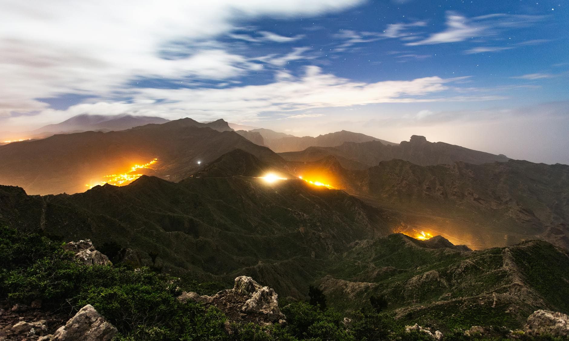 Beautiful nightscape of Tenerife mountains with glowing lights and starry sky.