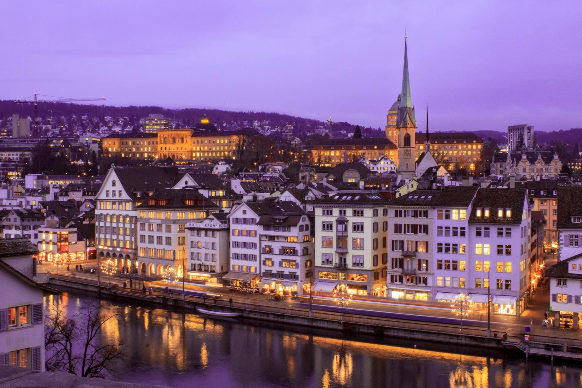 Stunning cityscape of Zurich at twilight with illuminated buildings and a serene river view.