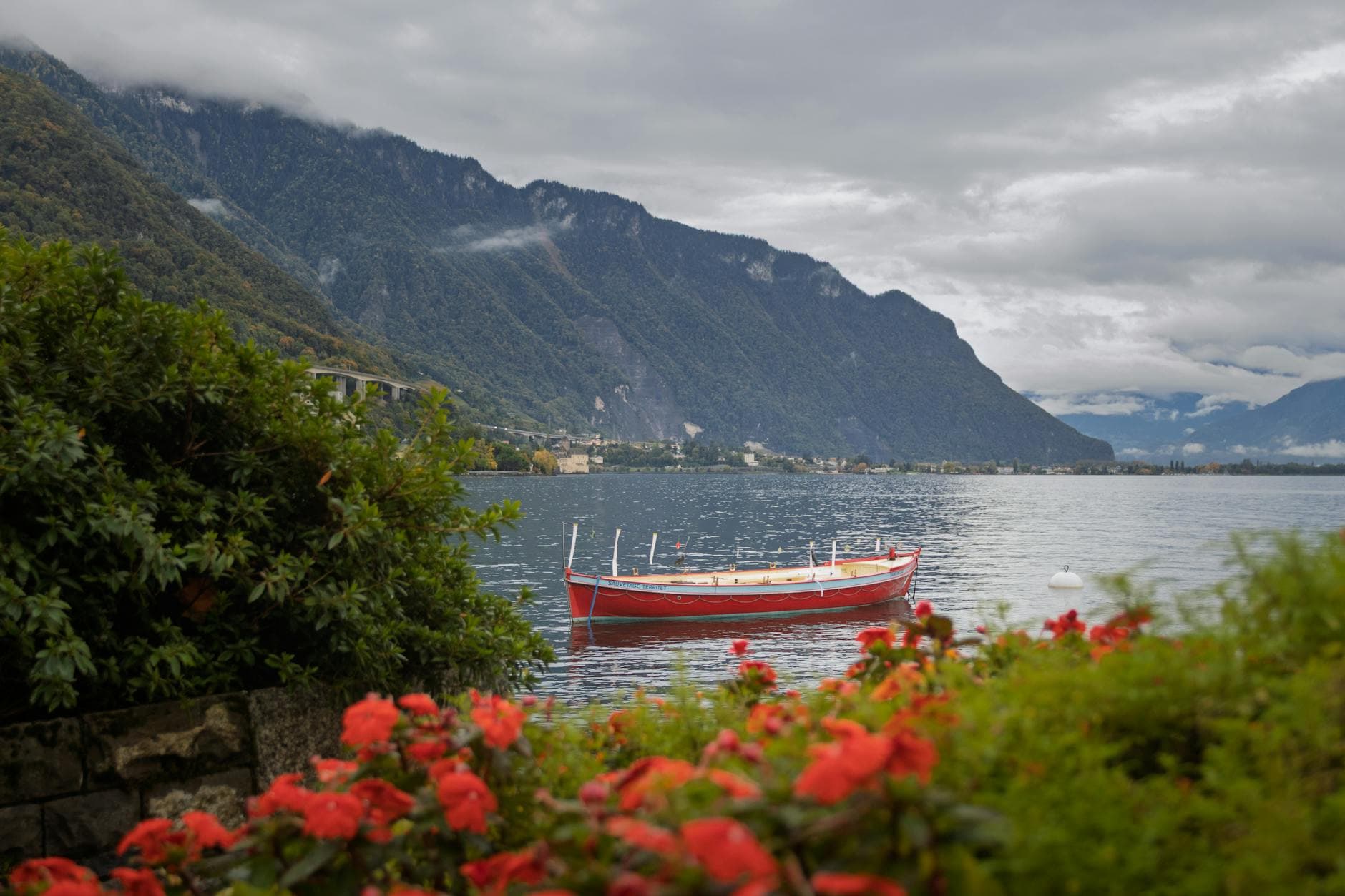 A colorful red boat on Lake Geneva with alpine backdrop in Montreux, Switzerland.