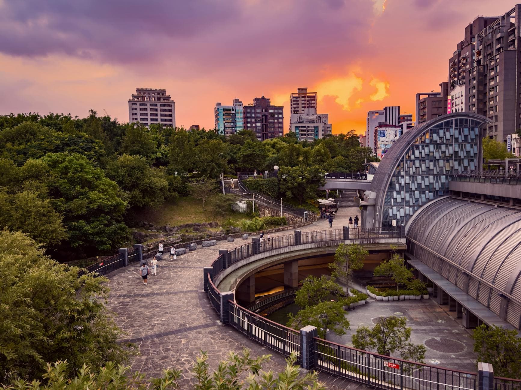 A stunning view of Taipei's urban landscape with a vibrant sunset backdrop and green park setting.