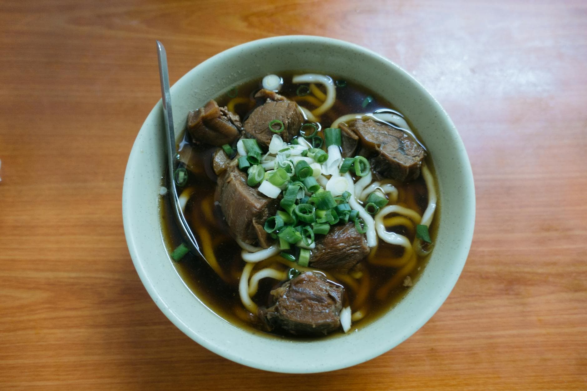 Savor the flavors of authentic Taiwanese beef noodle soup garnished with green onions.