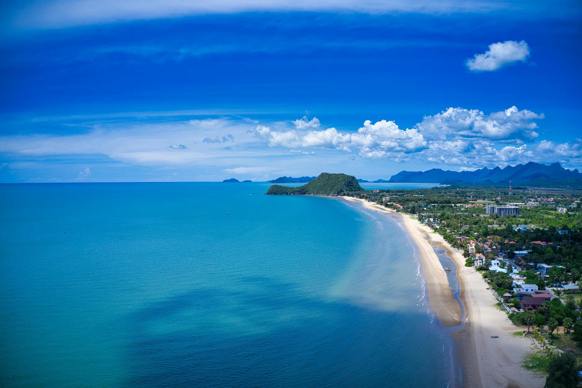 A breathtaking aerial view of Pak Nam Pran Beach, Thailand with clear blue waters and vibrant skies.