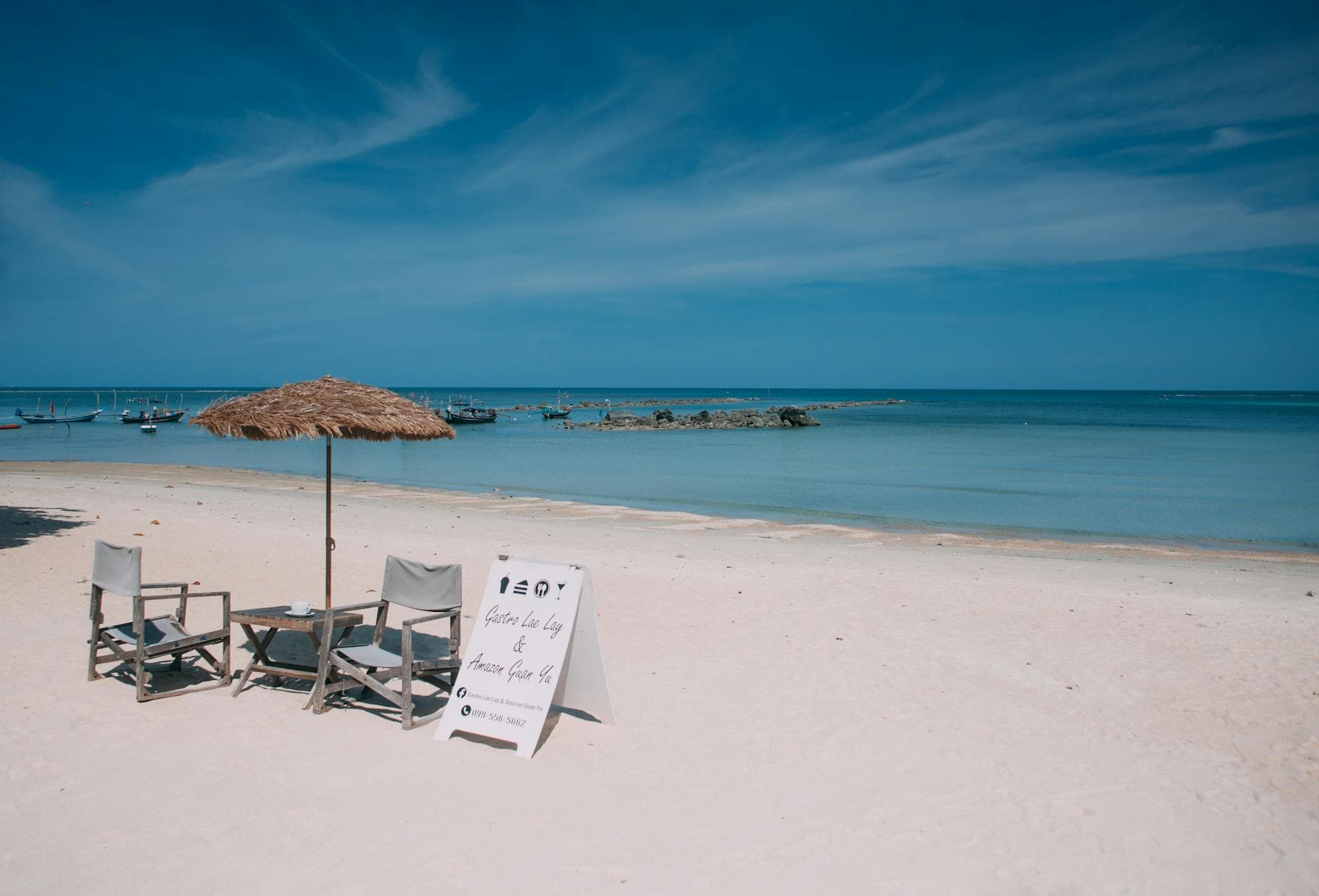 Relaxing beach view on Koh Samui with chairs and parasol under the sunny sky.