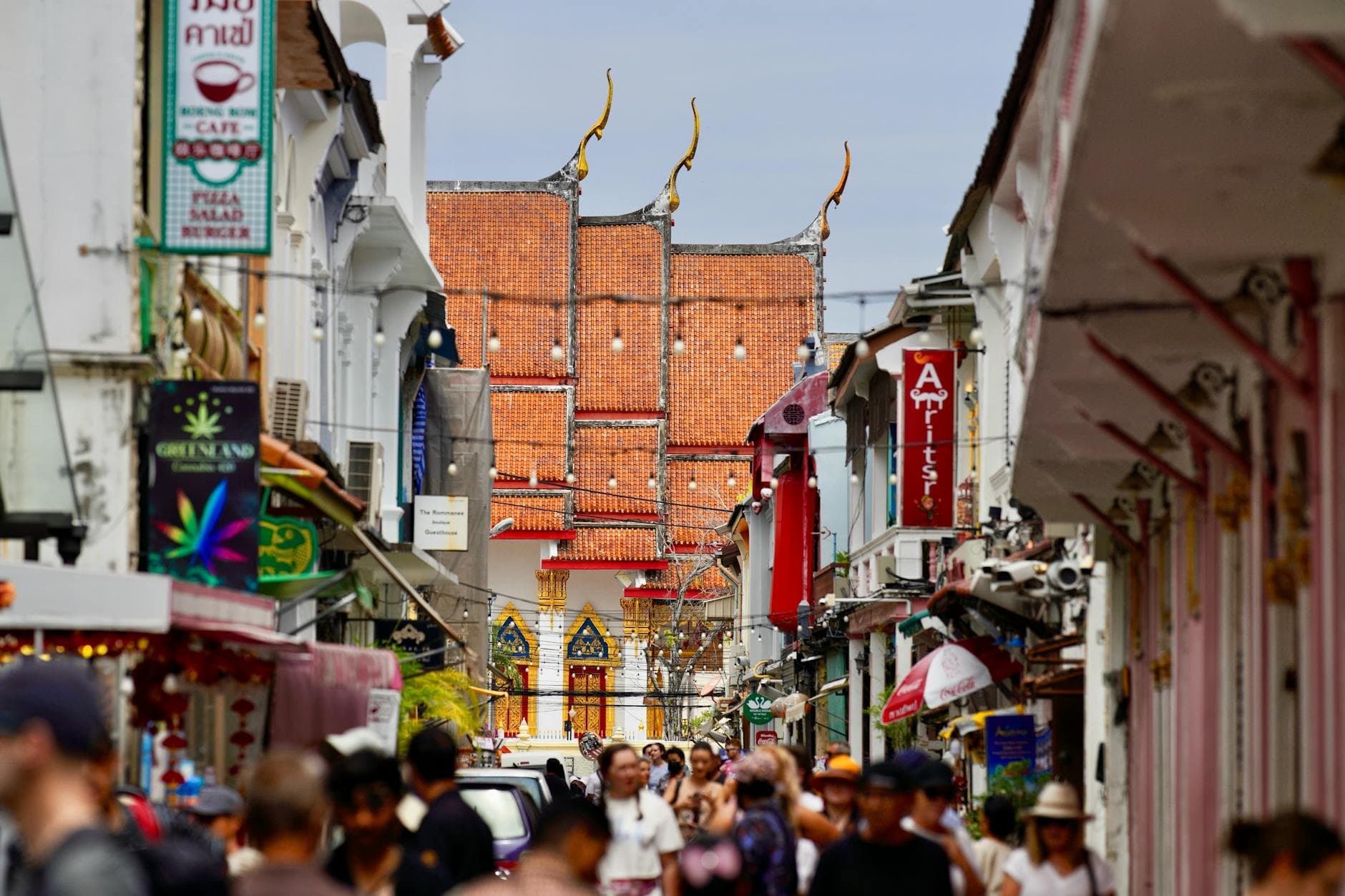 Vibrant street scene in Phuket, Thailand, showcasing traditional architecture and a busy crowd.