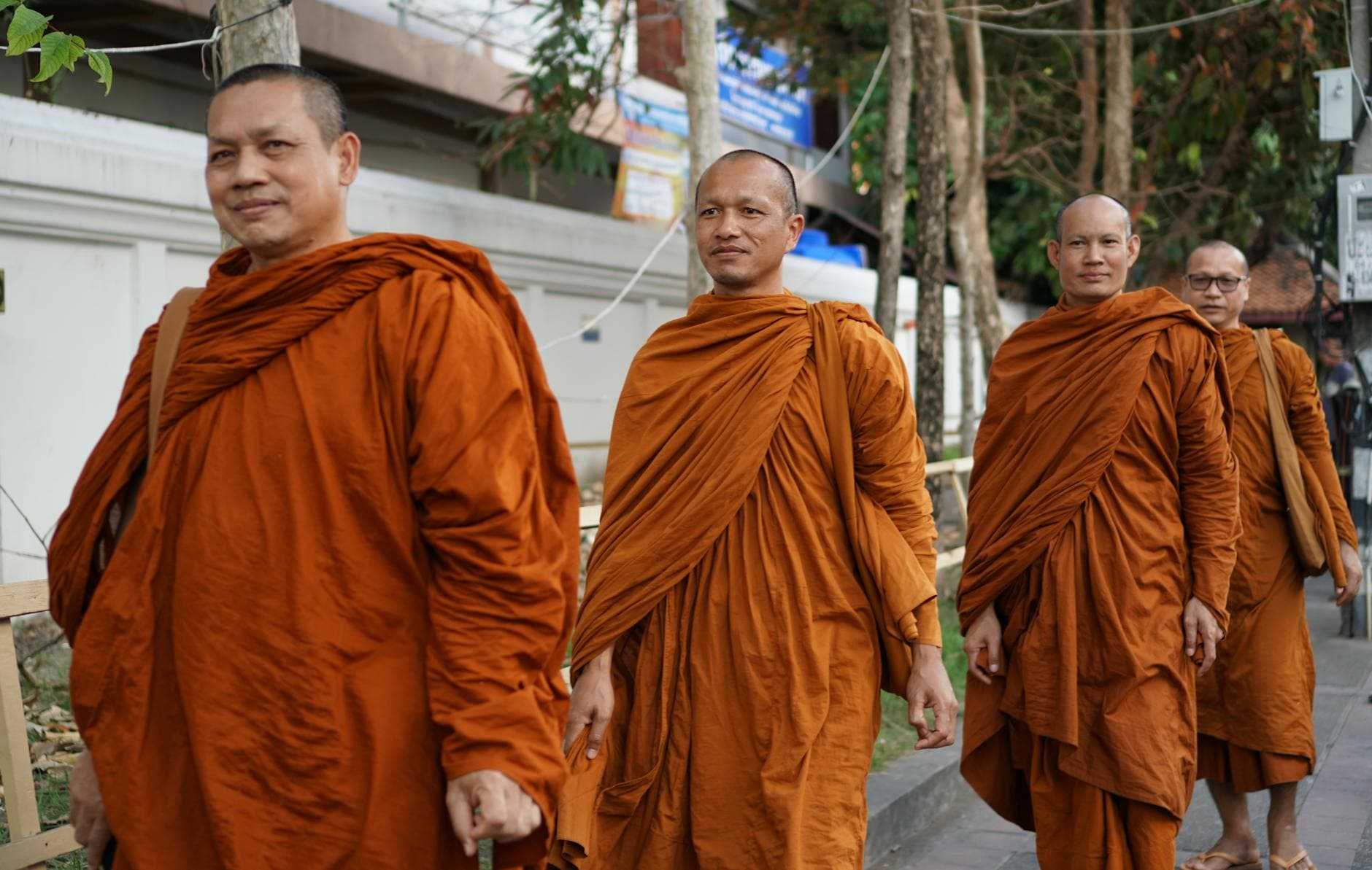 Group of Buddhist monks in traditional robes walking outdoors in Chiang Mai, Thailand, promoting cultural heritage.
