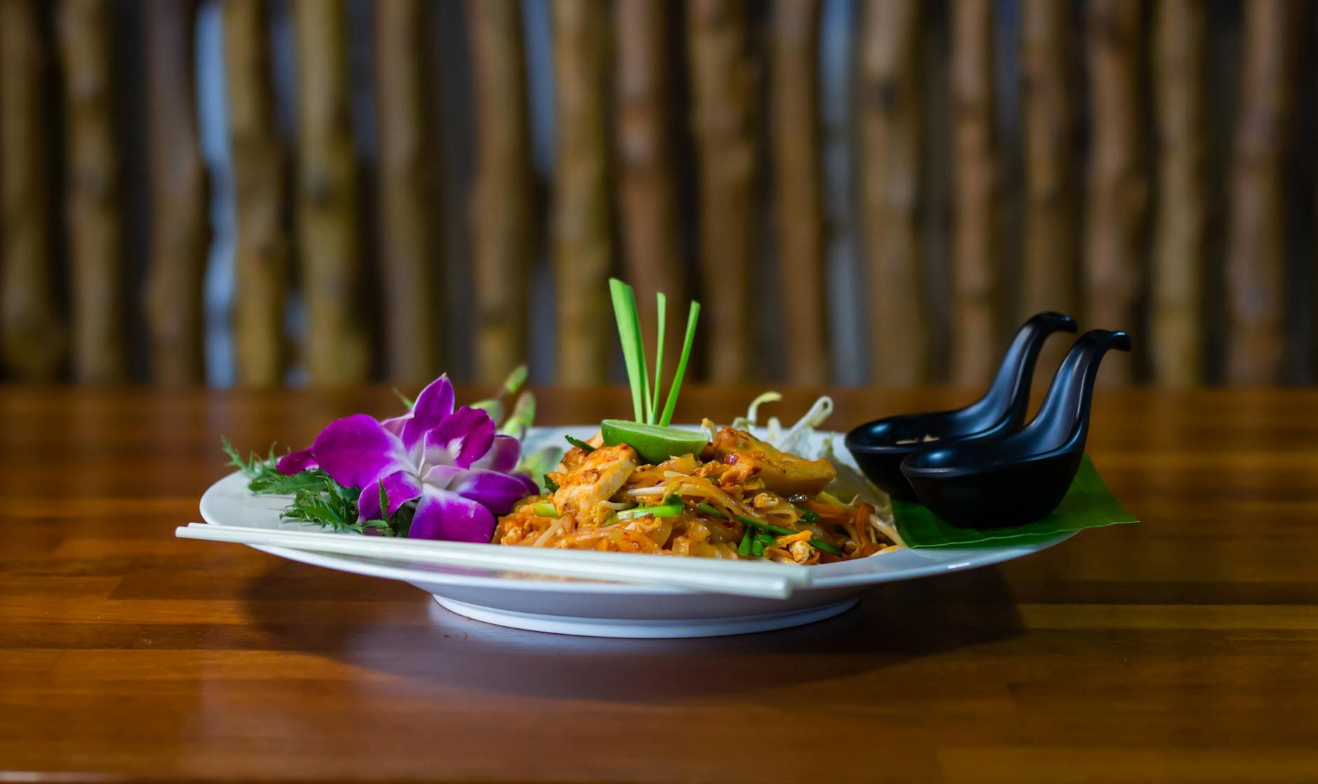 Close-up of a traditional Thai Pad Thai dish with vibrant floral garnishes, exuding a tasty and appetizing look.