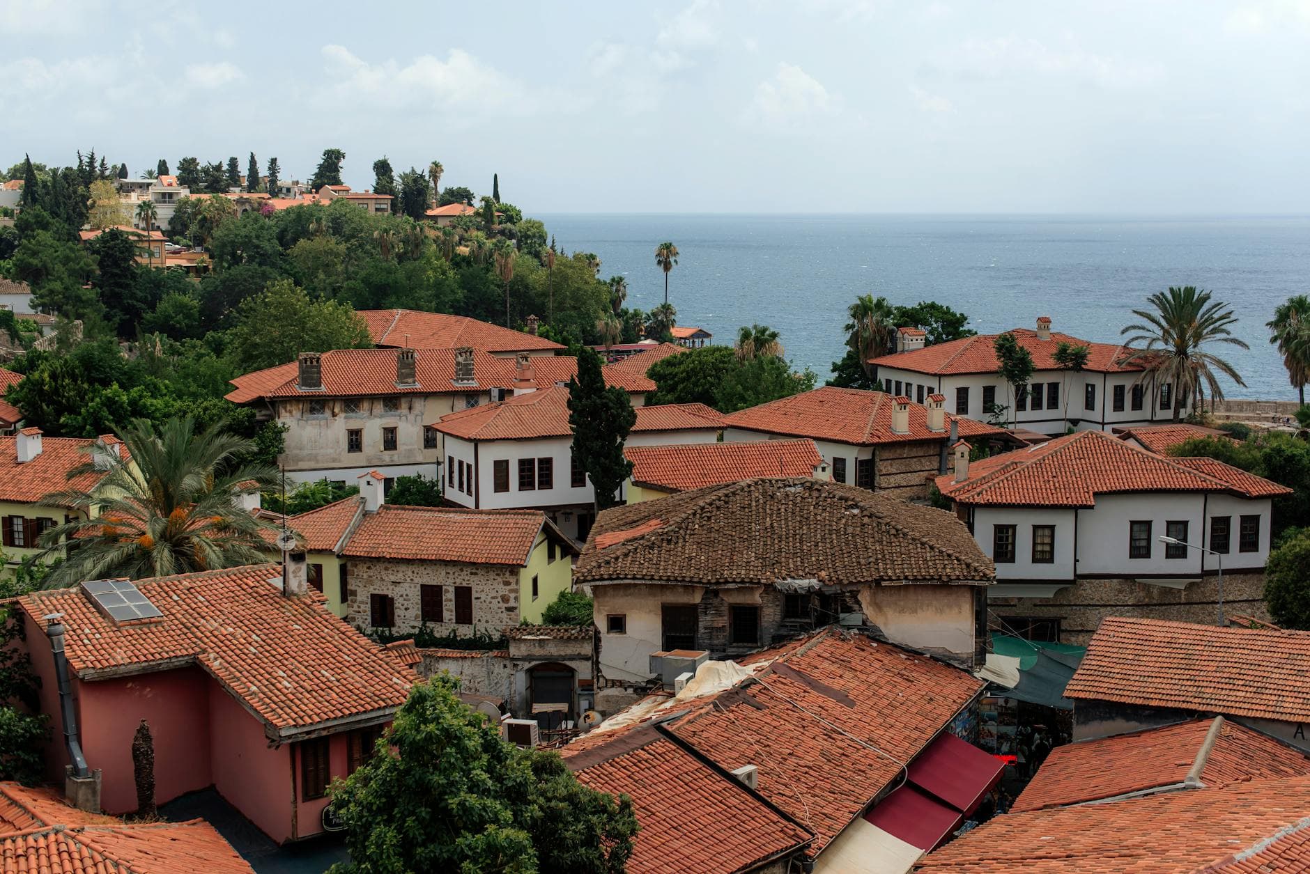 Charming view of Antalya's historic rooftops with the Mediterranean Sea in the background.