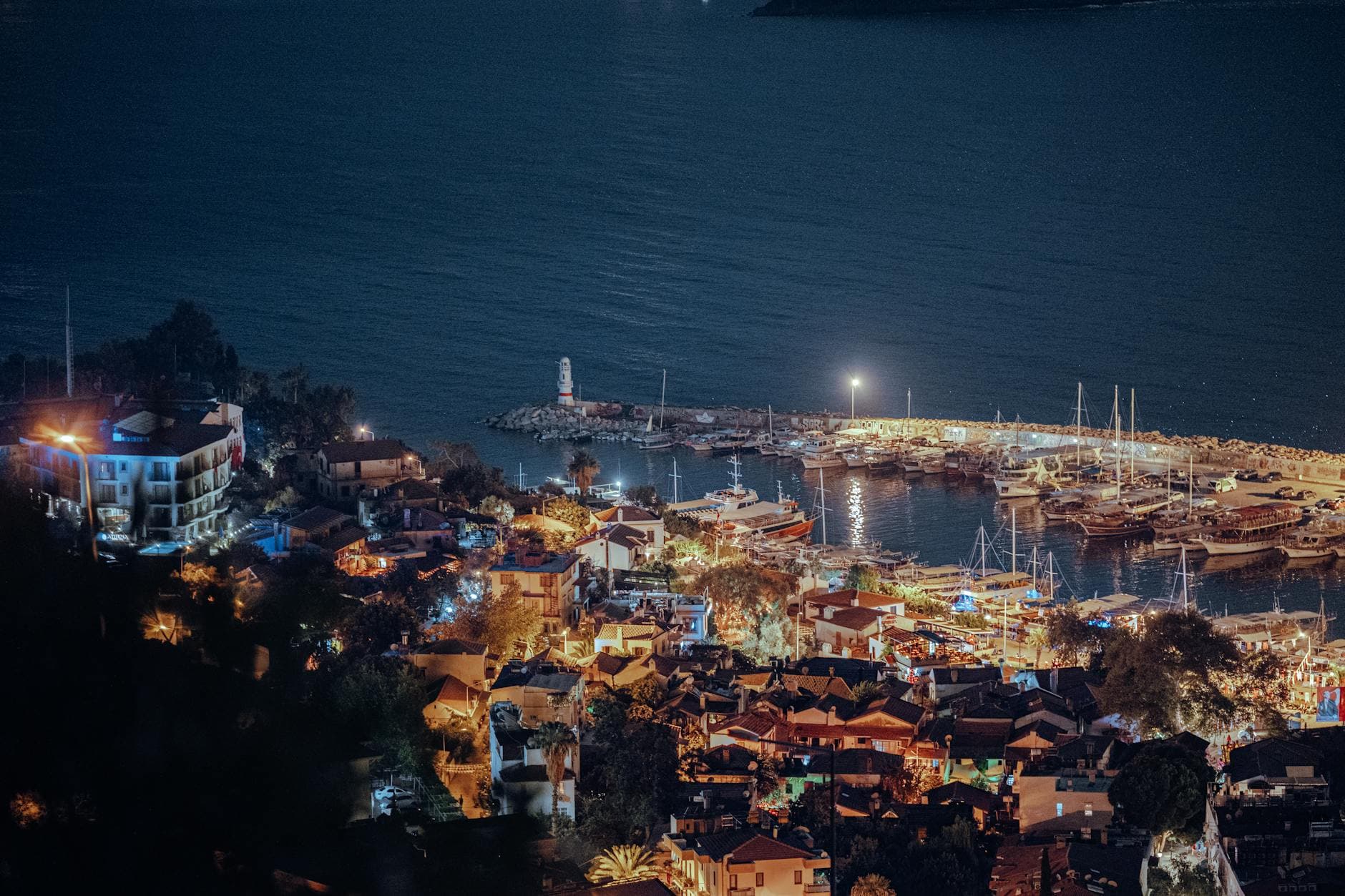 Scenic aerial view of illuminated Antalya marina with boats and town at night in Türkiye.