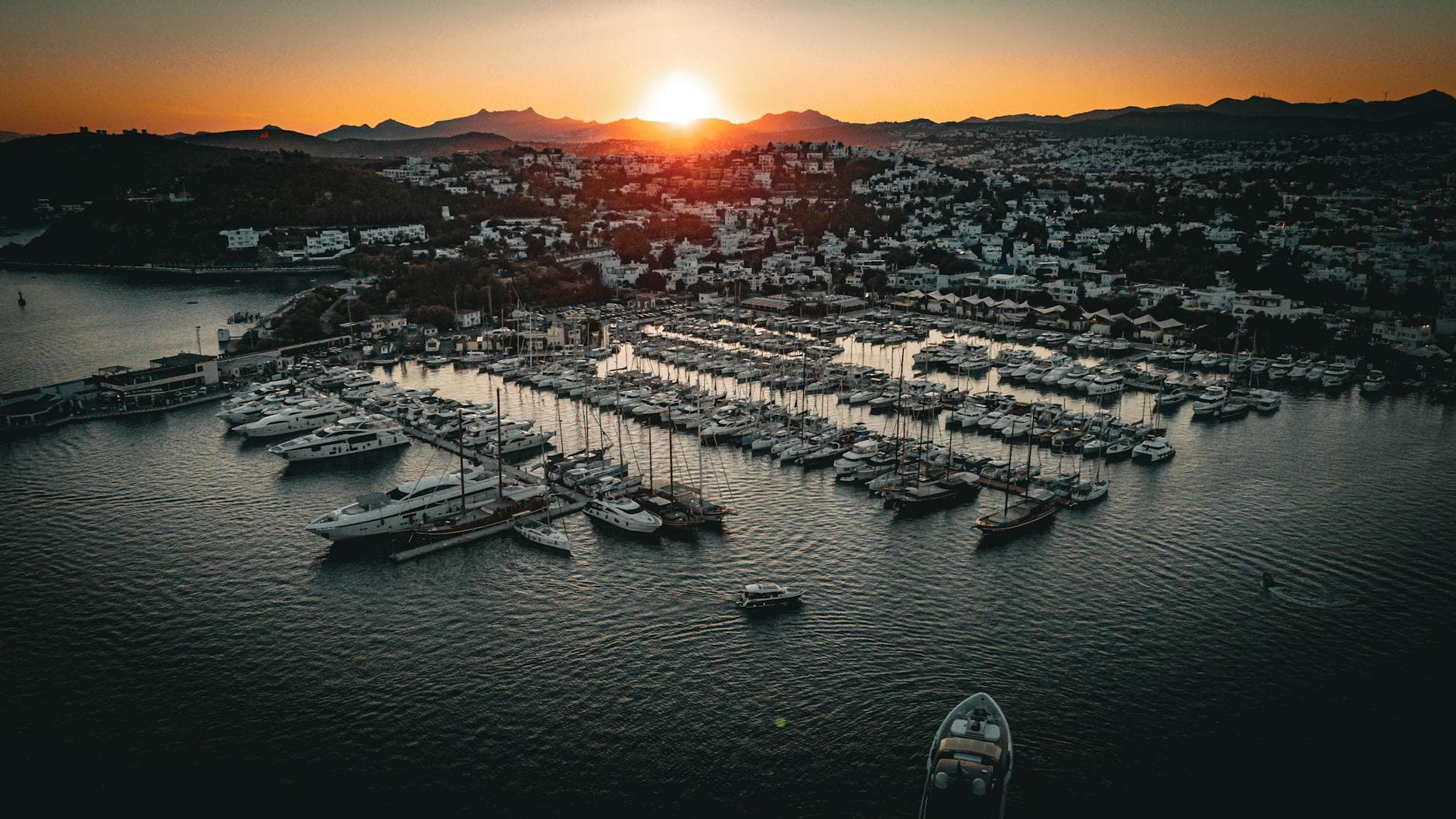 Aerial view of Bodrum Marina with boats and yachts at sunset, capturing the vibrant coastal atmosphere.