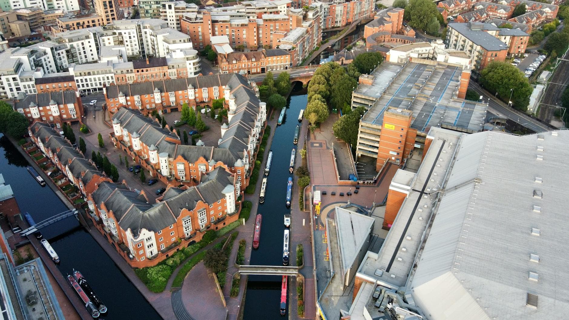 Aerial shot of Birmingham, UK showcasing canals, red-brick houses, and modern buildings.