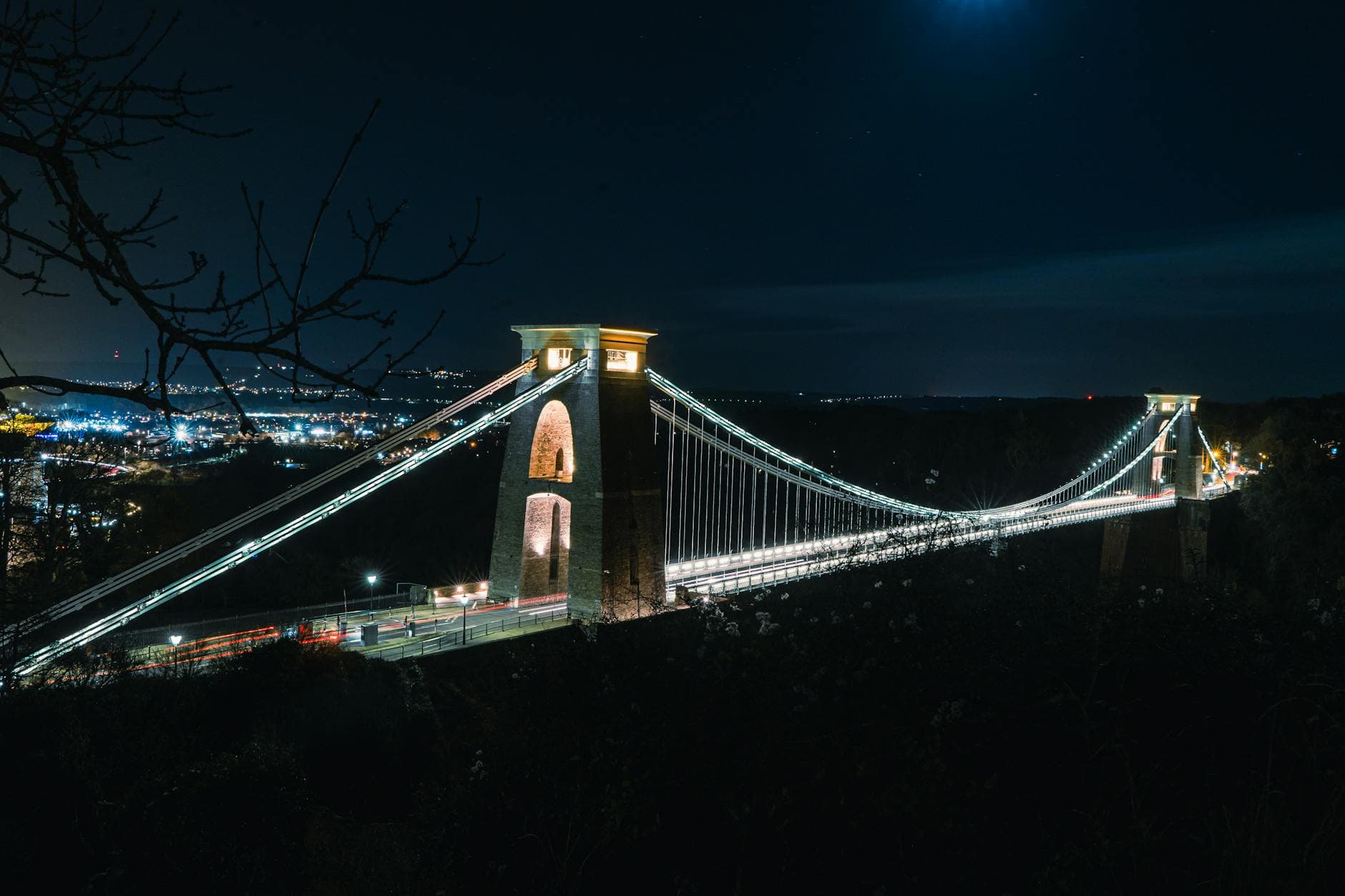 Stunning aerial view of Clifton Suspension Bridge illuminated against the night sky in Bristol.