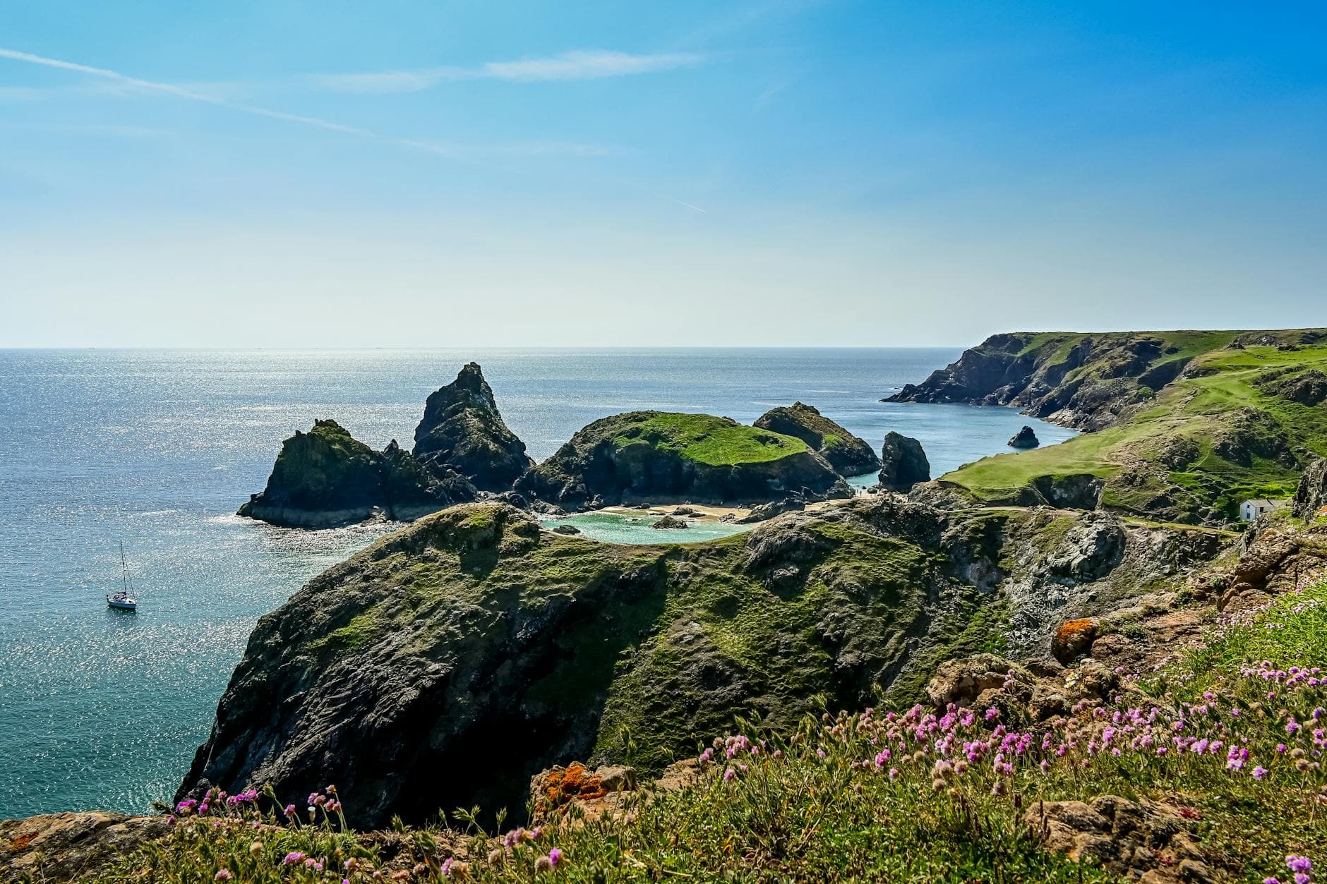 Breathtaking view of Kynance Cove's rugged coastline and turquoise waters under a clear blue sky.