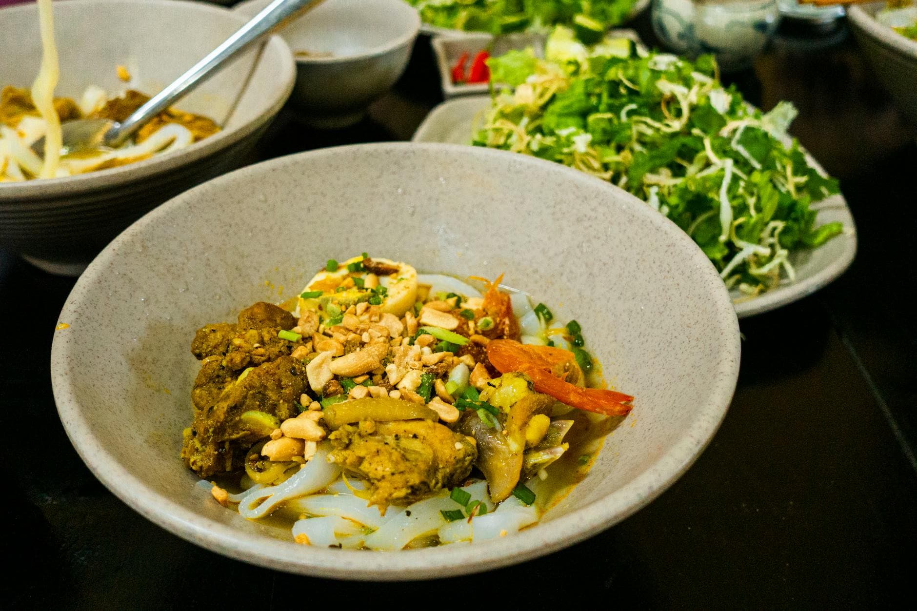 Close-up of Mi Quang noodles with fresh herbs and vegetables, a Vietnamese specialty.