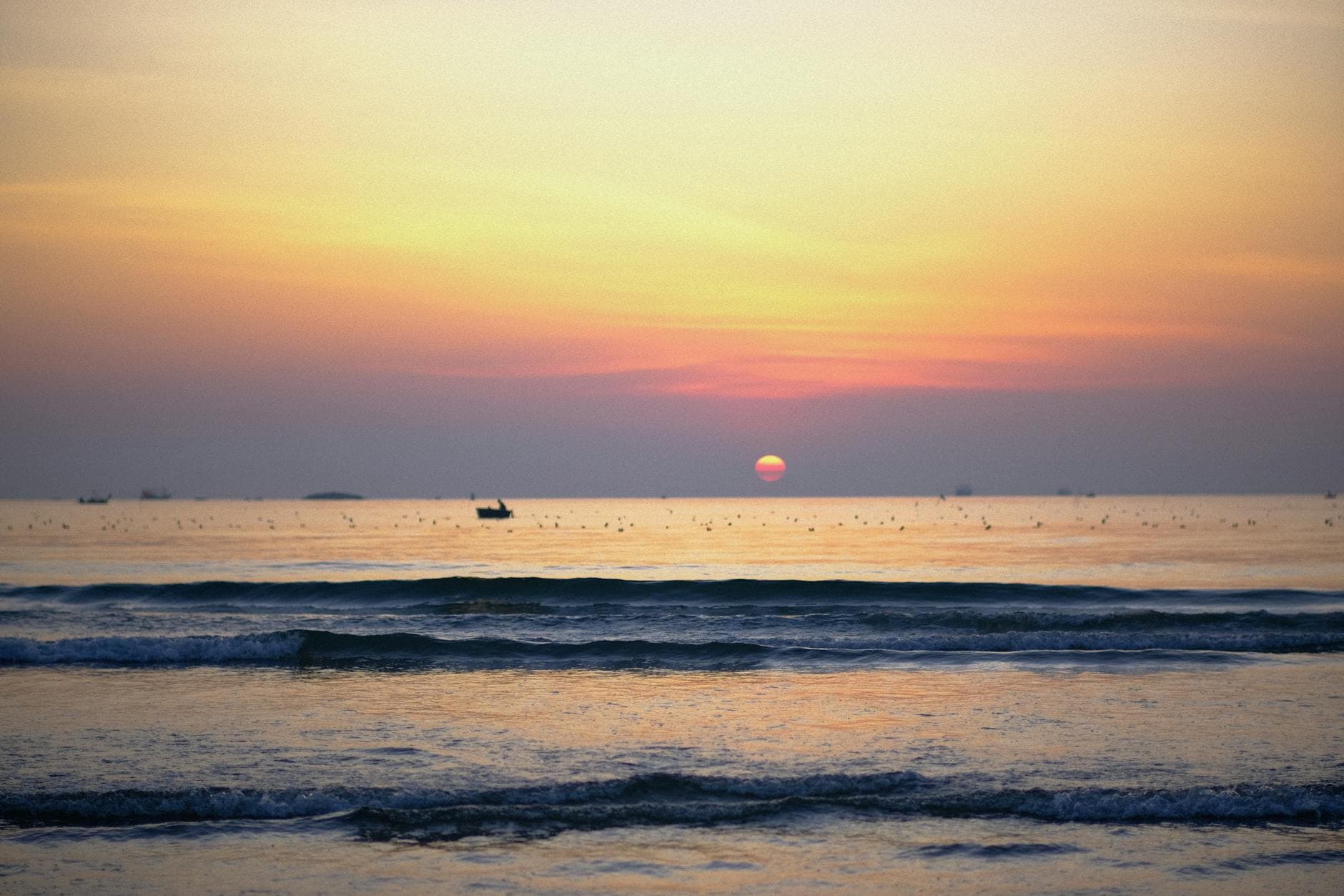A breathtaking sunrise over the calm ocean waves at Đà Nẵng beach, Vietnam.