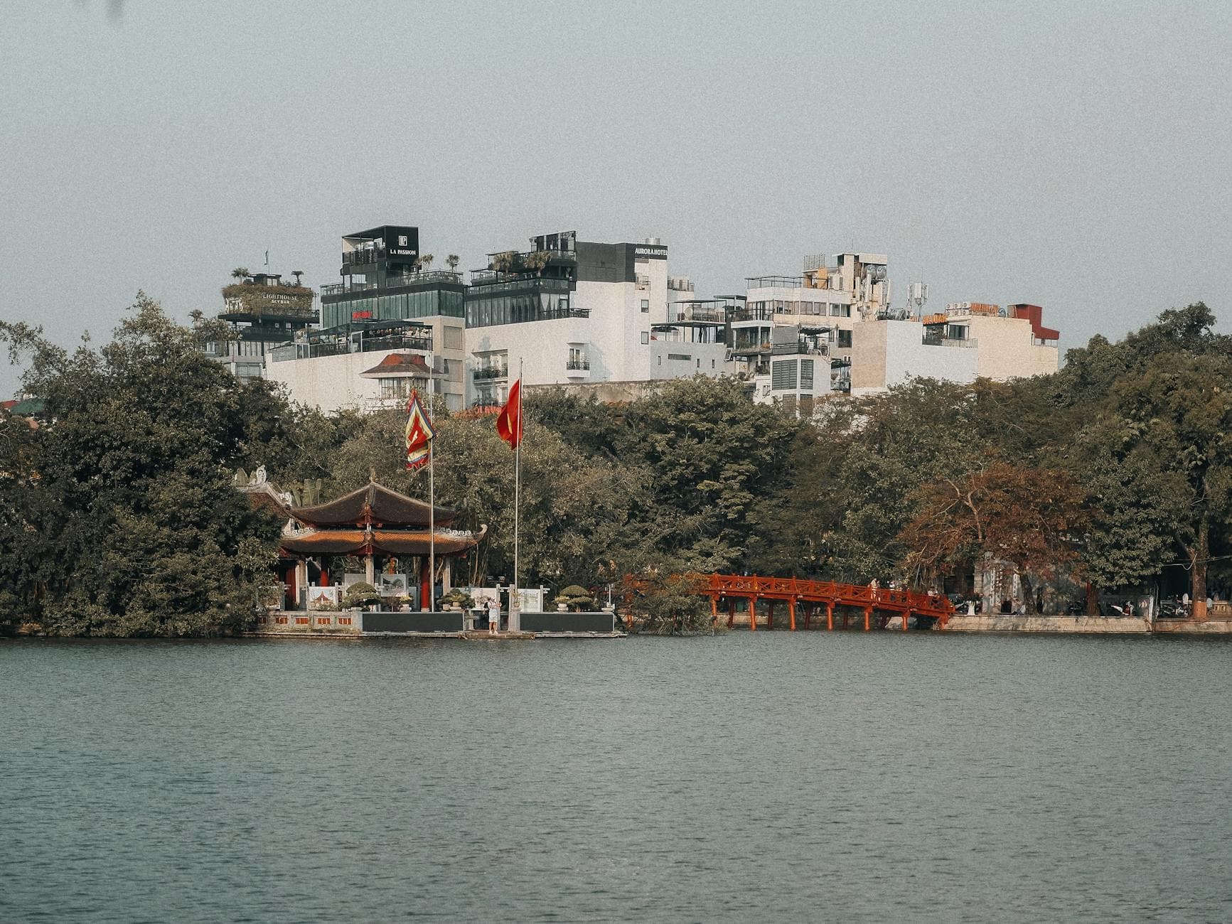 Scenic view of Hoàn Kiếm Lake with the iconic red bridge and vibrant cityscape in Hanoi, Vietnam.