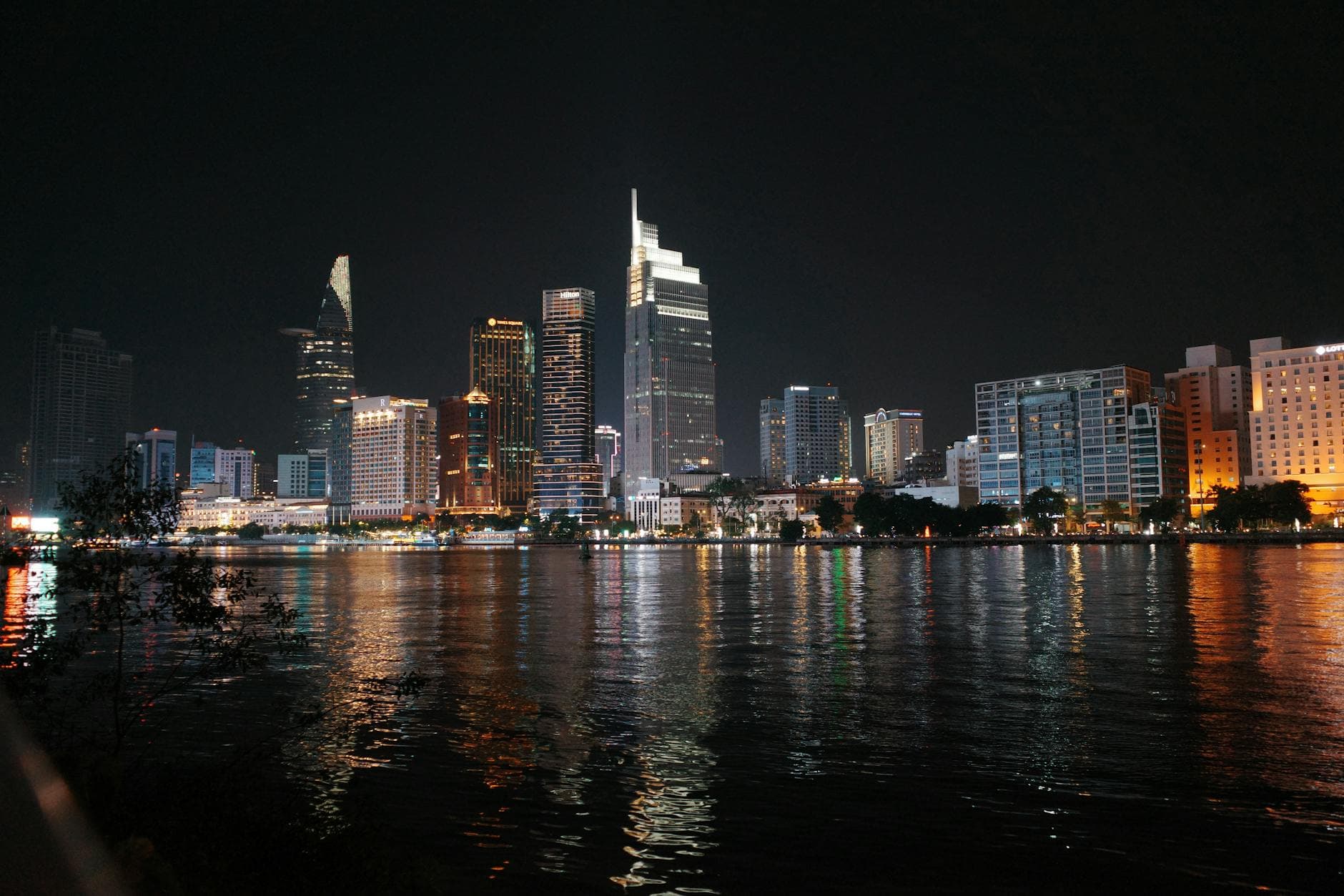 Stunning night view of Ho Chi Minh City's skyline with vibrant reflections on the Saigon River.