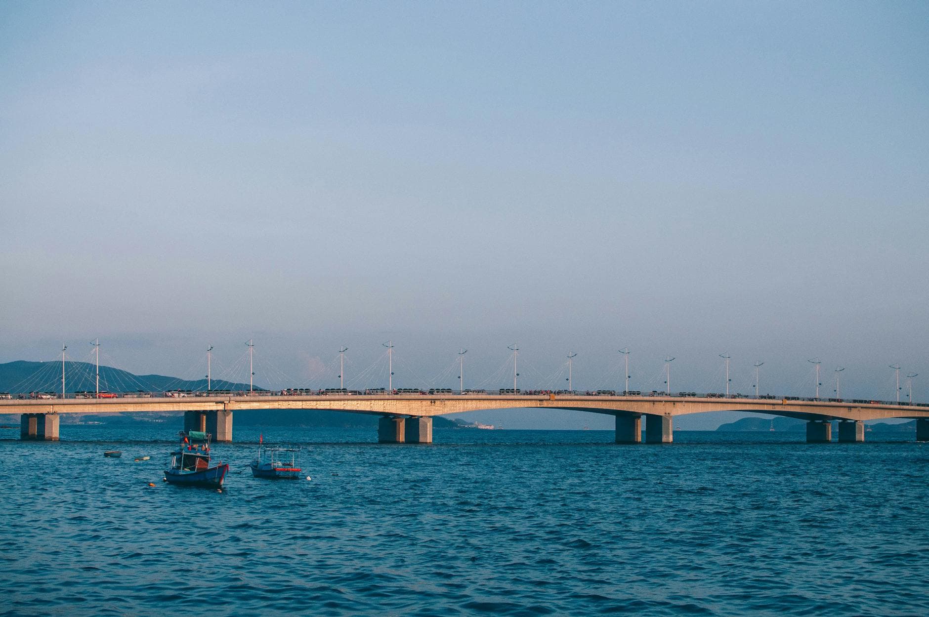 Peaceful view of Thi Nai Bridge spanning blue waters under a clear sky in Nha Trang, Vietnam.