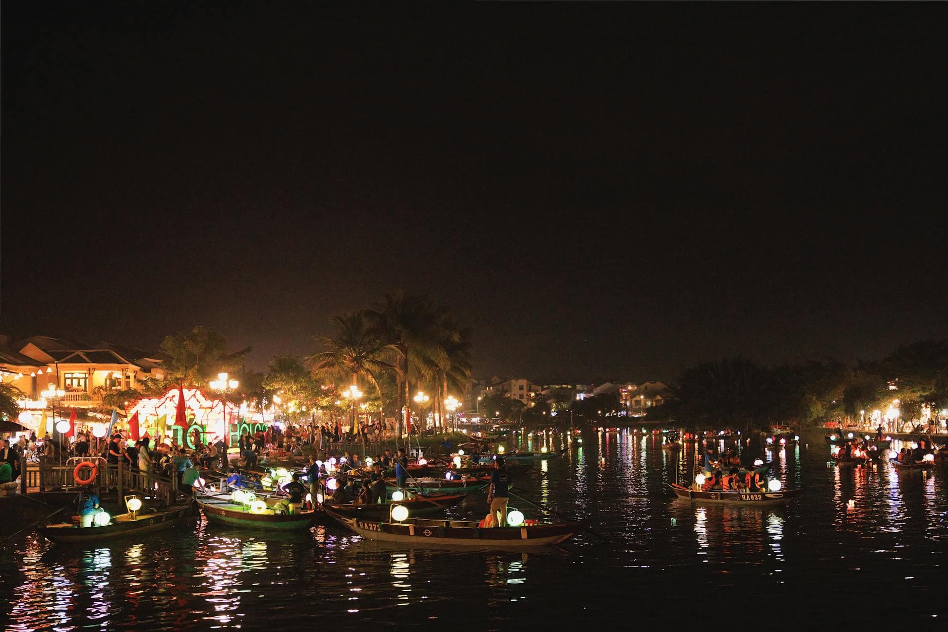 Vibrant night scene showcasing bustling riverside festivities in Hoi An Ancient Town, Vietnam.